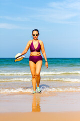 Woman in purple bikini walk on beach