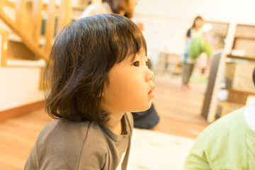 保育園で先生の話を聞く女の子の幼児