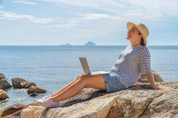 Woman is working on a laptop at a scenic location