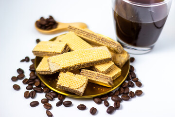 Chocolate wafer cookies on a gold plate with coffee beans and a drink