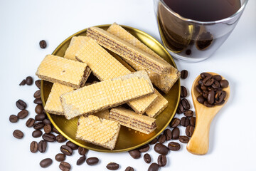 Chocolate wafer cookies on a gold plate with coffee beans and a dark drink