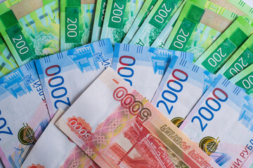 different denominations Russian banknotes are spread out on flat surface. image showcases colorful 200, 2000 and 5000 ruble notes, highlighting their unique designs. close up.