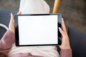 Close up woman student holding tablet with both hands reading or watching video as sitting in cafe.