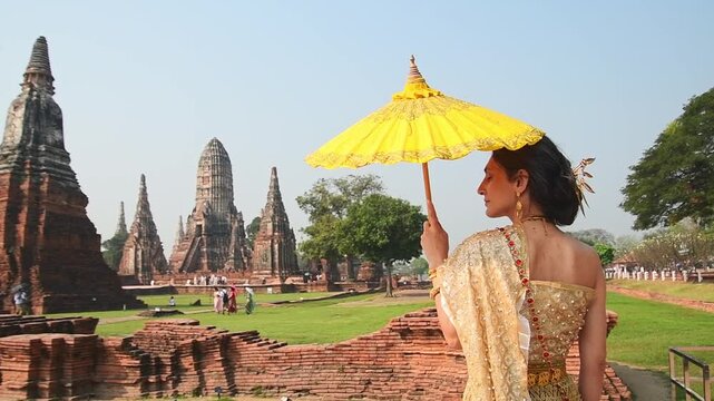 Thailand, Ayutthaya - march 15th, 2023: Woman in traditional Thai dress pose sightseeing visit ancient Buddha statue.Ayutthaya historical park. UNESCO World Heritage Site
