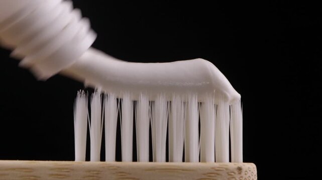 Bamboo toothbrush with white toothpaste on bristles against black background, eco friendly dental hygiene concept for oral care, sustainable lifestyle, natural product and teeth cleaning

