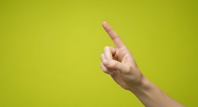 A single human hand with the index finger pointing upwards against a plain green background.