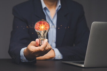 Businessman holding light bulb with brain symbol for innovation idea.