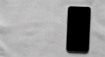 A black smartphone lying on a textured gray surface with a large empty space on the left side