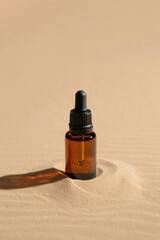 Naklejka premium Essential oil bottle on sand background