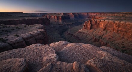 Vast, layered canyon vista with sunlit cliffs at dawn, shadows deepening within