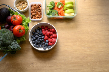 Top view of fresh ingredients with blueberries, raspberries, almonds, and vegetables on wooden table