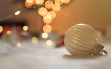 Clean christmas bauble on white wool with bokeh lights background.