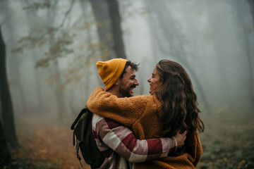 Happy couple embracing in misty autumn forest