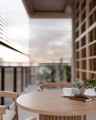 Coffee and notebook with pot plants on wooden table at balcony or terrace with blinds and evening sky.