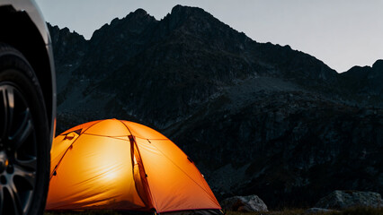 Tent illuminated in mountainous terrain