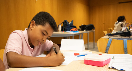Afro young male student concentrating, writing notes in a classroom setting