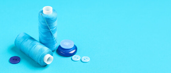 Spools of threads and buttons on blue background with space for text