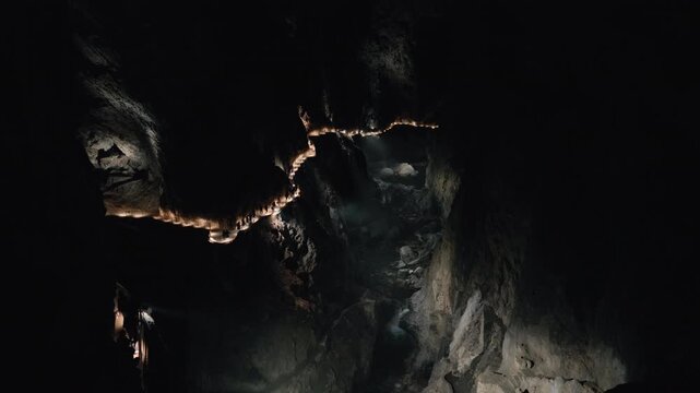 Dark and moody cave scene with glowing lights guiding through Slovenia&rsquo;s iconic &Scaron;kocjan Caves. A perfect visual for fantasy, exploration, or documentary use.