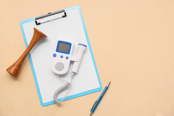 Fetal doppler with pinard stethoscope, clipboard and pen on yellow grunge background