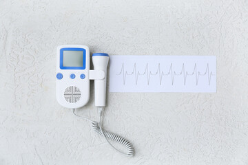 Fetal doppler with cardiogram on white grunge background