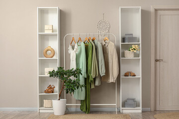 Interior of stylish hallway with clothes rack, door and folding screen
