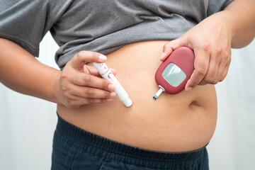 Asian woman injecting herself diabetes injecting insulin in stomach at home.