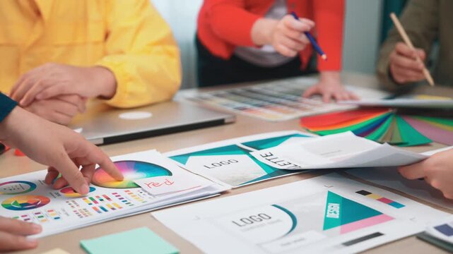 A dynamic workspace where a design team collaborates on logo and color selection. Professionals engage with vibrant materials, showcasing teamwork in creative processes. SACTR