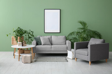 Interior of stylish room with grey sofa, armchair and blank frame