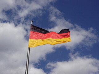 German flag (black-red-gold) waving against blue sky and clouds