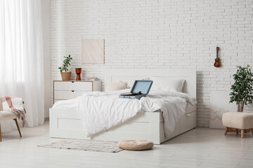 Interior of light bedroom with retro record player on cozy bed