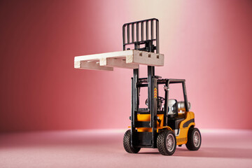 toy forklift with wood pallet against pink background.