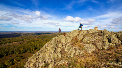 Mature tourists on the rocky peak of Yanguzey on the Irendyk ridge in the Southern Urals on a summer day