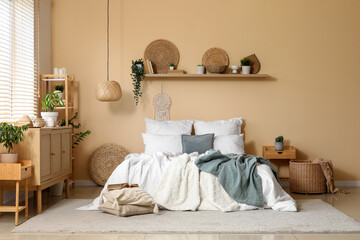 Interior of stylish bedroom with cozy bed, wooden cabinet and houseplants on shelf
