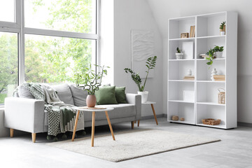 Interior of stylish living room with grey sofa, big window and bamboo stems on coffee table