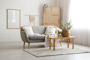 Interior of stylish living room with grey sofa, wardrobe and bamboo stems on coffee table