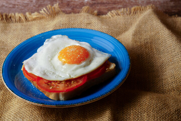 Protein-rich breakfast with fried egg, fresh tomato, and toast on rustic burlap
