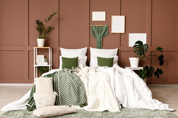 Interior of stylish bedroom with cozy bed, houseplants and frames