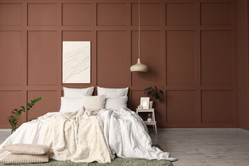 Interior of stylish bedroom with cozy bed, houseplants and painting