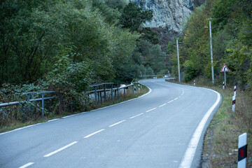 Curvy mountain road surrounded by green forest and dramatic cliffs