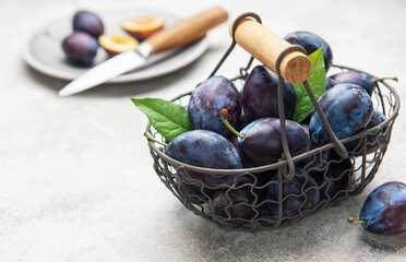 Fresh plums in basket with sliced fruit