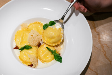 Eating ravioli with creamy cheese sauce and basil
