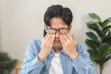 Eye problem concept, fatigue asian young man tired eyes, irritated rubbing eye dry relief vision...