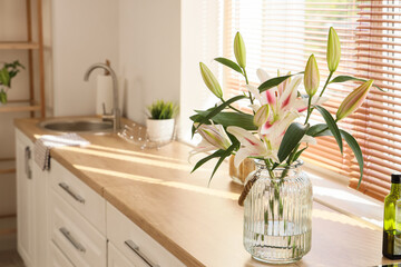 Vase with beautiful lily flowers on counter in kitchen, closeup