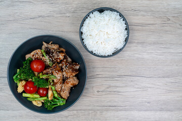 Stir-fried red snapper with teriyaki sauce and Rice, broccoli, tomatoes, asparagus, and baby corn on wooden table, Top view.
