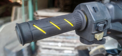 Close-up of motorcycle throttle handle with yellow stripe on black rubber grip. Focused on transportation and mechanical details.