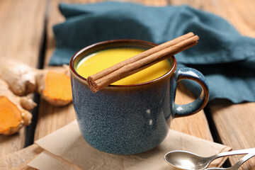 Cup of healthy turmeric drink on wooden background, closeup
