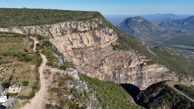 Aerial view of Tundavala Gap near Lubango, Angola, showing dramatic cliffs and vast green valleys under clear blue sky.