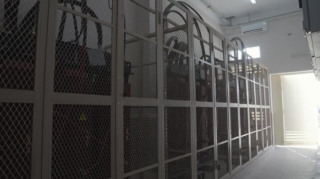 An interior shot of an industrial power room. Large, high-voltage electrical cabinets, transformers, or servers are secured behind protective metal mesh cages.