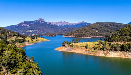 Naklejka premium Majestic lake vista, verdant hills and mountains under a clear sky