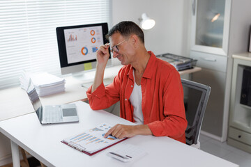 Mature man analyzing business data documents at desk